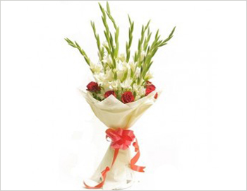 A vertical arrangement of roses-carnations and gladioli with greens.; An assortment of flowers, roses, carnations and gladioli, tastefully arranged with a cane backdrop and filled with greens